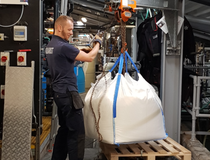 A Deep Crew member stood smiling as they hoist one of the salt bags up in the air.