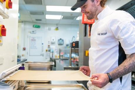 A chef using the Wrapmaster dispenser in a kitchen.