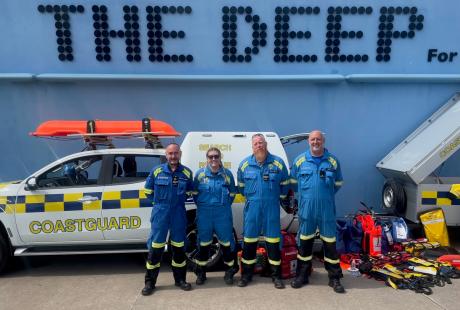 HM Coastguard team stood outside the front of The Deep building with their coastguard vehicle parked beside them.