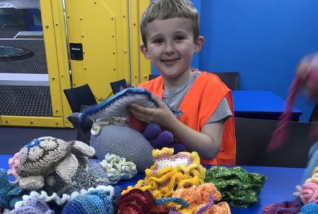 A young boy smiling as he explores the sensory crochet table